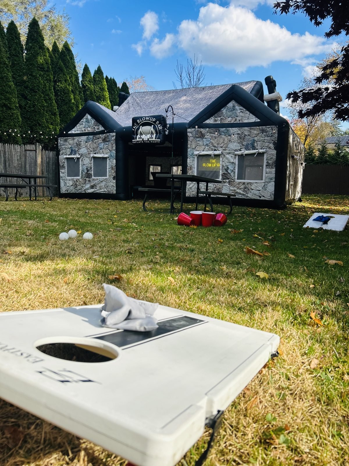 The Blow Up Bar inflatable pub in a backyard with lawn games out front
